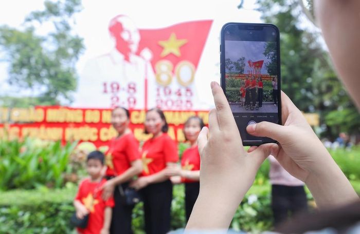 Check-in trong sắc cờ đỏ sao vàng, người dân lưu lại khoảnh khắc ý nghĩa tại khu vực pano có hình ảnh Bác Hồ. Ảnh: Thành Phương-TTXVN