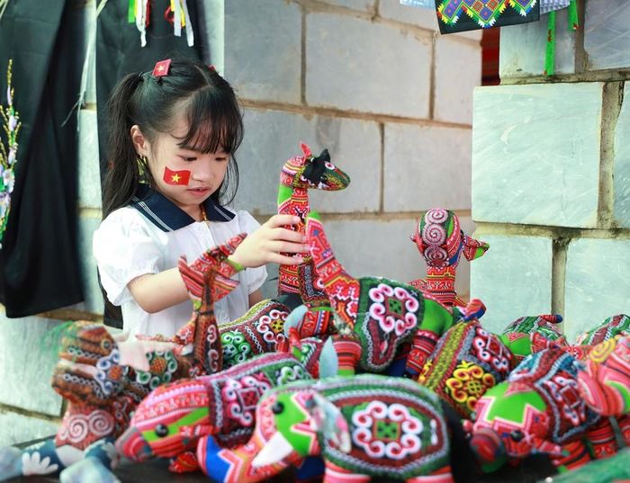 Em nhỏ thích thú với đồ chơi thủ công của đồng bào Mông. Ảnh: Vân Chi/TTXVN
