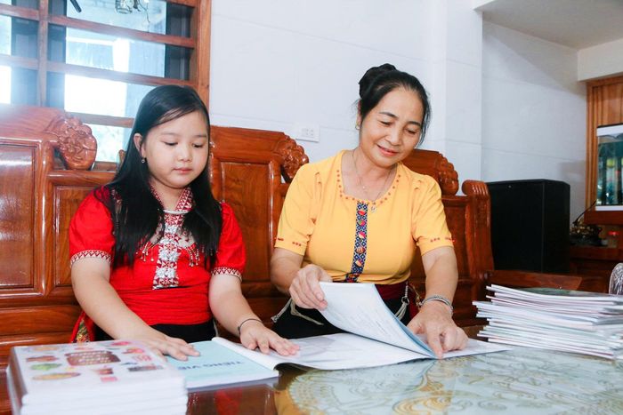 Em Võ Thị Phương Thảo - học sinh lớp 4, Trường Tiểu học Thạch Giám cùng bà ngoại cẩn thận bọc từng cuốn sách chuẩn bị chào đón năm học mới. Ảnh: Đình Tuân
