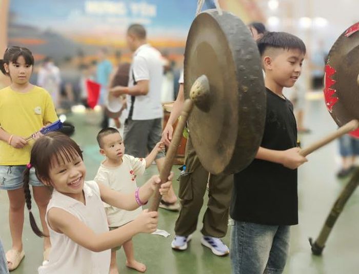Các "du khách nhí" tranh nhau trải nghiệm gõ chiêng tại gian hàng Đăk Lăk.