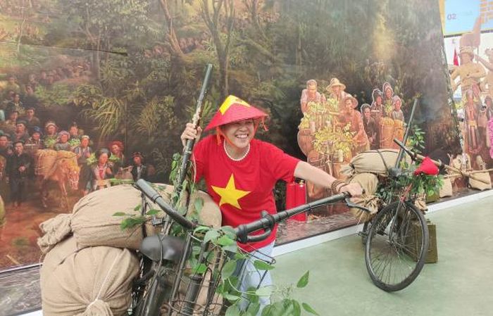 Khách tham quan "nhập vai" với chiếc xe thồ - phương tiện vận chuyển thô sơ trong Chiến dịch Điện Biên Phủ.