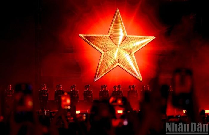 Điểm nhấn xúc động của concert “Tổ quốc trong tim” là khoảnh khắc hàng chục nghìn khán giả cùng đứng dậy, hướng về lá cờ đỏ sao vàng và đồng thanh hát vang Quốc ca. Ảnh: Báo Nhân Dân