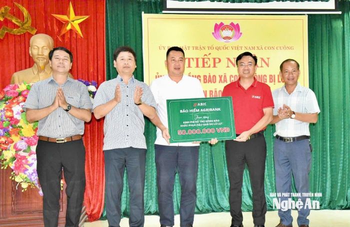 Tổng Biên tập Báo và phát thanh, truyền hình Nghệ An Trần Minh Ngọc và ông Phạm Văn Tuyển - Bí thư chi bộ, Giám đốc Công ty Bảo hiểm Agribank chi nhánh Nghệ An trao 50 triệu đồng hỗ trợ sửa chữa nhà ở cho người dân xã Con Cuông. Ảnh: Hoài Thu