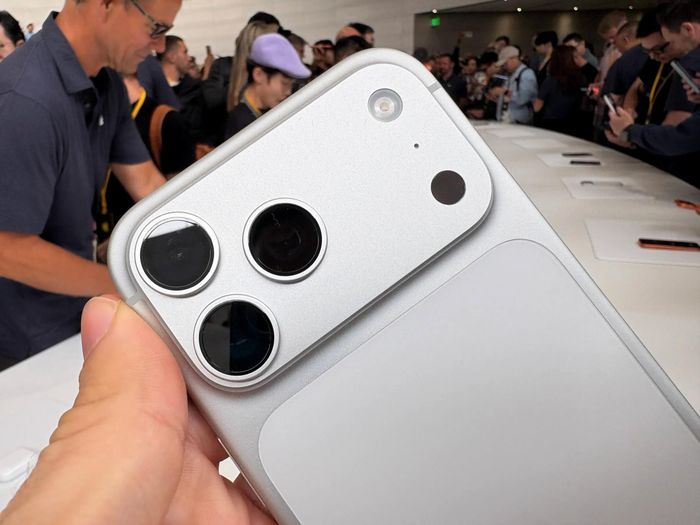  Cụm camera trên iPhone 17 Pro Max được thiết kế dạng thanh ngang, ôm trọn ba ống kính lớn tạo cảm giác đồng bộ và hiện đại. Bề mặt hoàn thiện mờ kết hợp chi tiết bóng loáng giúp thiết bị nổi bật ngay trong môi trường trưng bày. Ảnh: The Verge. 
