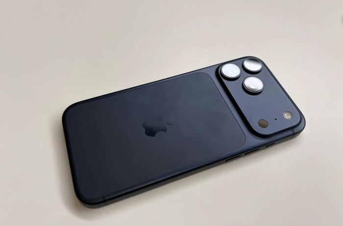  Phiên bản iPhone 17 Pro Max màu đen cho thấy sự liền lạc giữa mặt lưng kính và thanh camera ngang. Bề mặt bóng kết hợp cùng cụm ống kính lớn tạo điểm nhấn mạnh mẽ, mang lại vẻ sang trọng cho thiết bị. Ảnh: The Verge. 