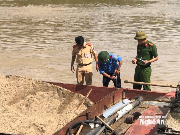 Lực lượng chức năng kiểm đếm khối lượng cát chở trên một tàu ven sông Lam. Ảnh: N.H