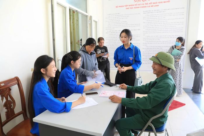 Hình ảnh cán bộ, thanh niên tình nguyện hướng dẫn người dân Hà Nội làm thủ tục hành chính khi chính quyền địa phương 2 cấp đi vào hoạt động. Ảnh: Phạm Hùng