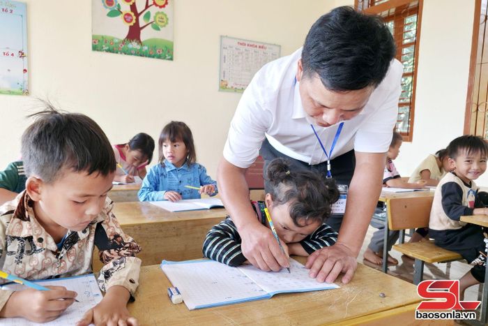 Thầy giáo Sồng A Lử hướng dẫn học sinh viết chữ.