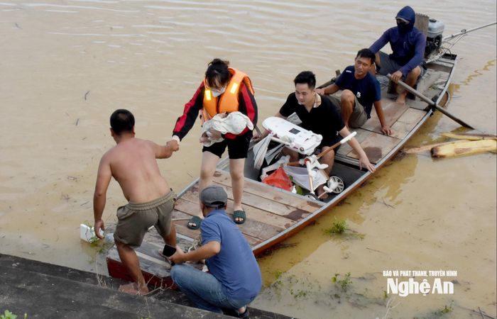 Một em bé sơ sinh cùng mẹ được hỗ trợ di chuyển đến vùng trong đê Tả Lam. Ảnh: Công Kiên