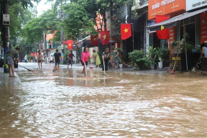 Người dân phố Bế Văn Đàn, phường Thục Phán (Cao Bằng) tranh thủ dọn dẹp khi nước bắt đầu rút. Ảnh: Chu Hiệu - TTXVN