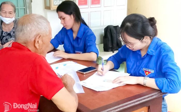 Đoàn viên thanh niên xã Dầu Giây hỗ trợ người dân đến giải quyết thủ tục hành chính sau khi mô hình chính quyền 2 cấp đi vào hoạt động. Ảnh: Nhật Quang