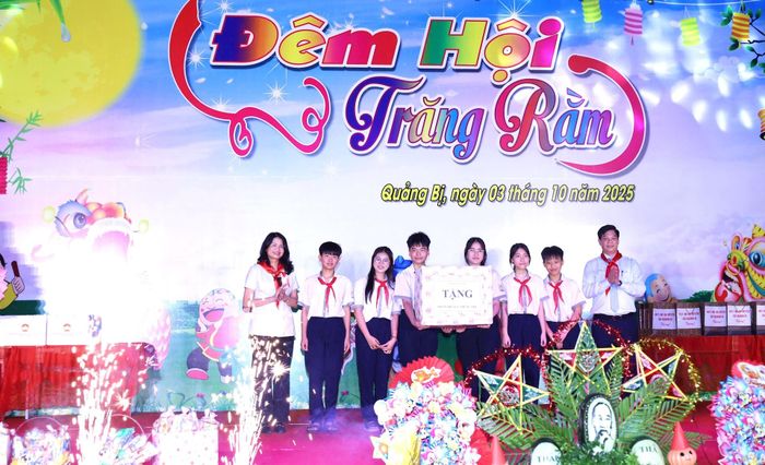Đại diện lãnh đạo thành phố và Bí thư Đảng ủy, Chủ tịch HĐND xã Quảng Bị Nguyễn Trường Năng trao quà của Thành ủy, HĐND, UBND, Ủy ban MTTQ Việt Nam thành phố Hà Nội cho thiếu nhi Quảng Bị. Ảnh: Kim Nhuệ