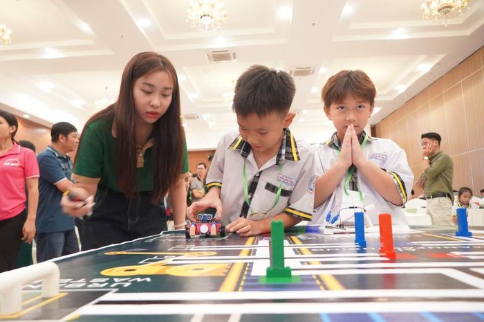  Ở mỗi bàn thi, có trọng tài giám sát về thời gian càng khiến cuộc thi càng thêm hấp dẫn. Trong ảnh là em Hứa Khánh Hưng đang chuẩn bị cho robot vào vạch đích, bên cạnh là đồng đội Trần Thiện Phú đang hồi hộp theo dõi. 