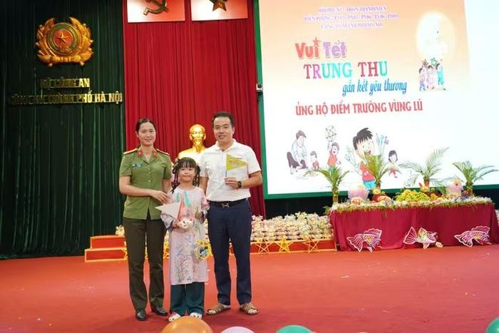Trung tá Vũ Thị Tứ, Trưởng Ban Phụ nữ CATP cùng em nhỏ trong “Phiên đấu giá Thương yêu”