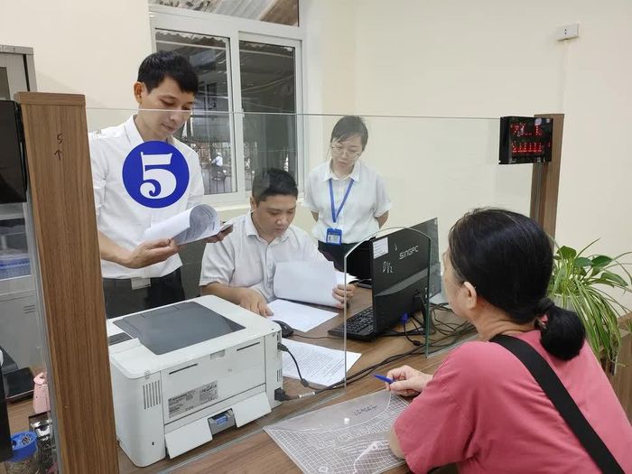 Các cán bộ chuyên môn hỗ trợ công chức giải quyết thủ tục hành chính cho người dân phường Nghĩa Đô (Hà Nội). Ảnh: Nguyễn Cúc-TTXVN