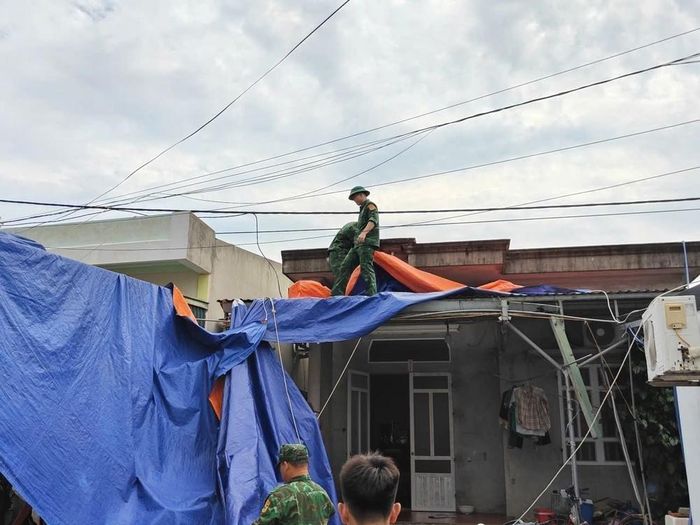 Cán bộ, chiến sĩ Đồn biên phòng Trà Cổ (Quảng Ninh) chằng chống nhà cửa, giúp dân chống bão. Ảnh: TTXVN phát