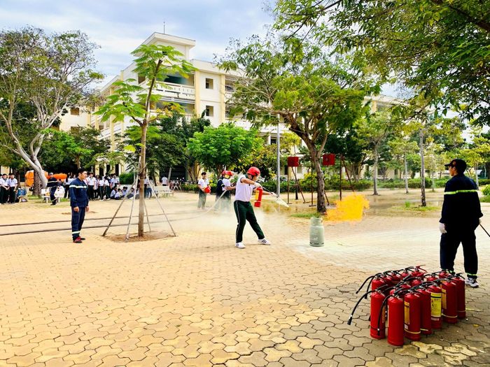 Các em học sinh được hướng dẫn thực hành sử dụng bình chữa cháy dập tắt bình gas đang cháy
