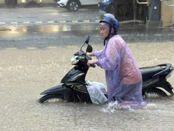 Tại phố Nguyễn Tuân, nước đã dâng cao khoảng 40 cm gây khó khăn cho việc đi lại của người dân. Ảnh: Quốc Lũy - TTXVN