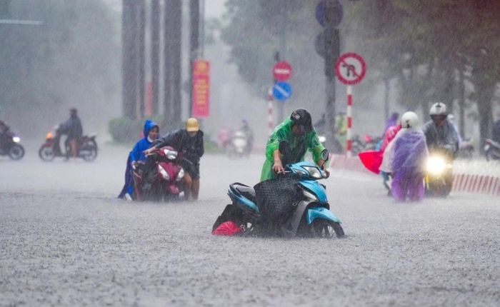 Người dân dắt bộ xe trong cơn mưa trên phố Nguyễn Hoàng. Ảnh: Tùng Đinh