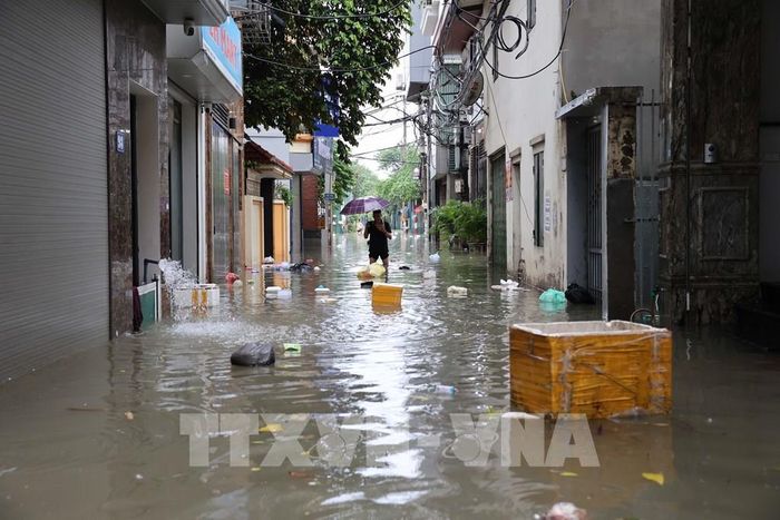 Nước ngập sâu, cuốn theo rác thải và các vật dụng trôi nổi trên phố Tân Triều. Ảnh: Vũ Quang - TTXVN