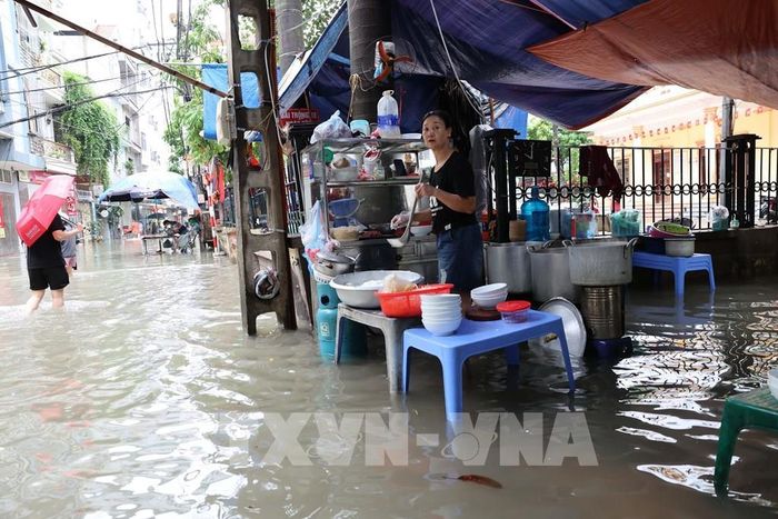 Người dân phố Triều Khúc kê cao bếp và các vật dụng để tiếp tục buôn bán trong cảnh ngập. Ảnh: Vũ Quang - TTXVN