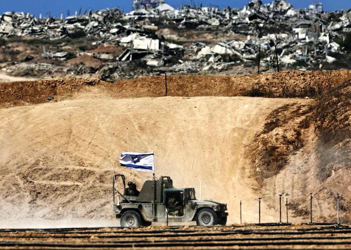 Xe quân sự của Israel chạy qua các tòa nhà bị phá hủy dọc biên giới với Dải Gaza. Ảnh: EPA