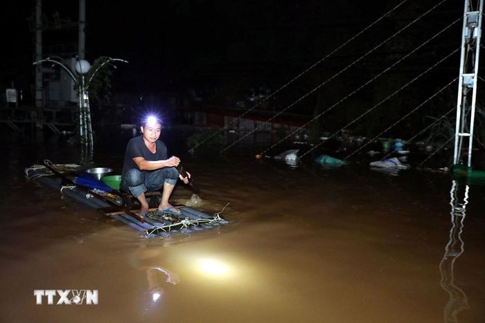 Người dân xã Thất Khê, tỉnh Lạng Sơn di chuyển bằng bè mảng qua Quốc lộ 4A đang bị ngập sâu trong đêm. (Ảnh: Văn Đạt/TTXVN)