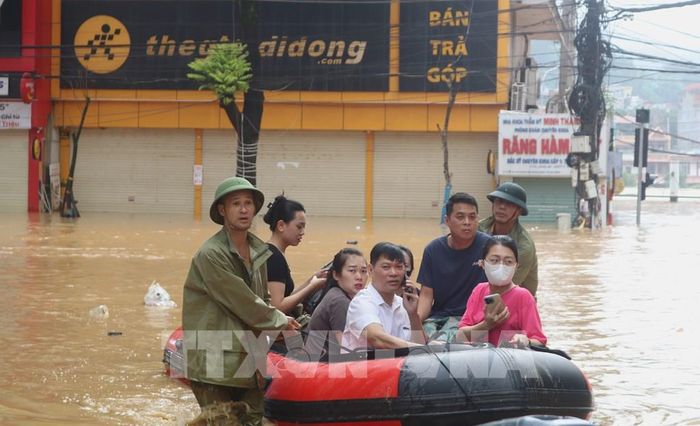 Lực lượng chức năng hỗ trợ người dân di chuyển trong vùng ngập lụt. Ảnh: Chu Hiệu-TTXVN