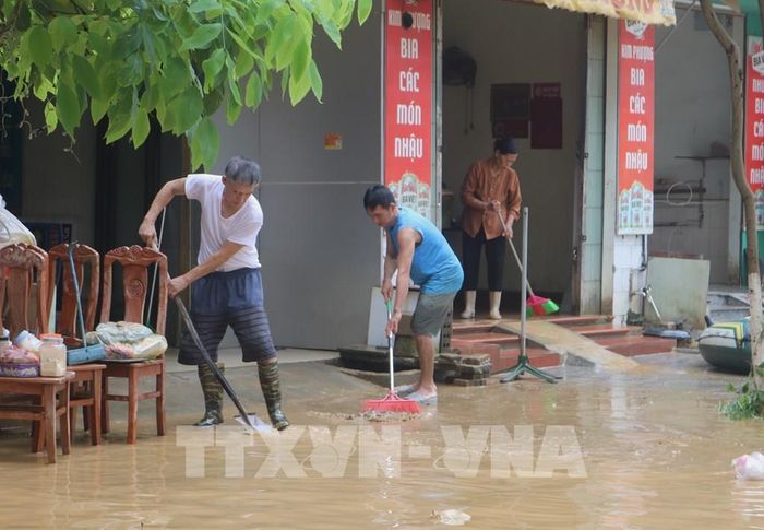 Người dân dọn dẹp bùn đất tại những nơi nước rút. Ảnh: Chu Hiệu-TTXVN