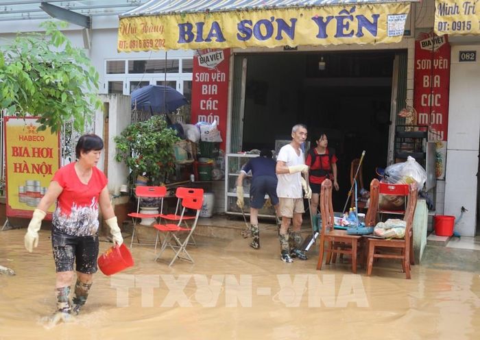 Người dân dọn dẹp bùn đất vào nhà do ngập lụt. Ảnh: Chu Hiệu-TTXVN