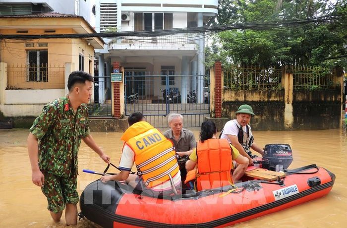 Lực lượng chức năng hỗ trợ người dân di chuyển trong vùng ngập lụt. Ảnh: Chu Hiệu-TTXVN