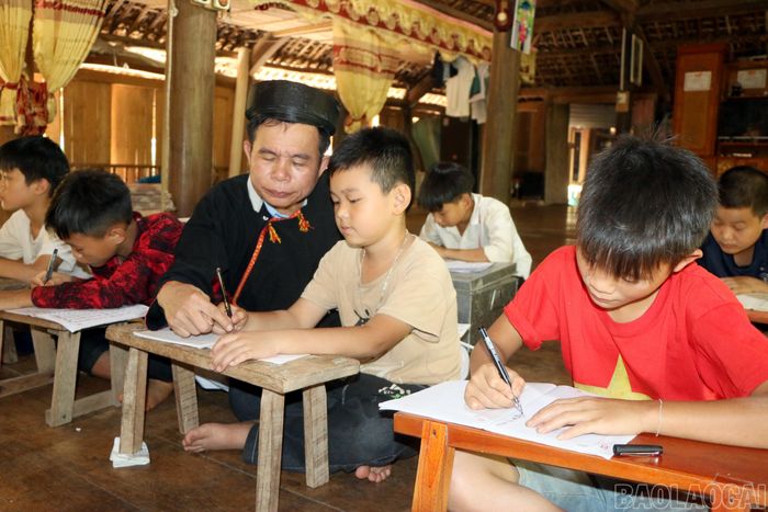  Trong không gian nhà sàn truyền thống, nghệ nhân ưu tú Hoàng Hữu Định (xã Yên Thành) kiên trì hướng dẫn các em nhỏ học viết chữ Dao cổ, một cách trao truyền di sản ngôn ngữ, thắp lên niềm tự hào dân tộc cho thế hệ mai sau. 