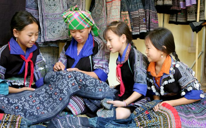  Phụ nữ Mông tỉ mỉ truyền dạy kỹ thuật thêu hoa văn trên nền vải chàm – một trong những biểu tượng đặc trưng của trang phục truyền thống. 