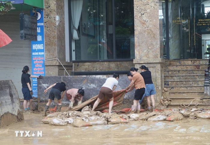 Người dân vùng ngập lụt tranh thủ dọn dẹp khi nước đã rút. (Ảnh: Chu Hiệu/TTXVN)