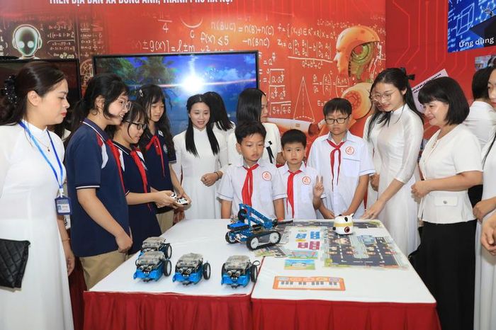 Học sinh và giáo viên trải nghiệm mô hình lập trình robot và ứng dụng công nghệ tại gian trưng bày.