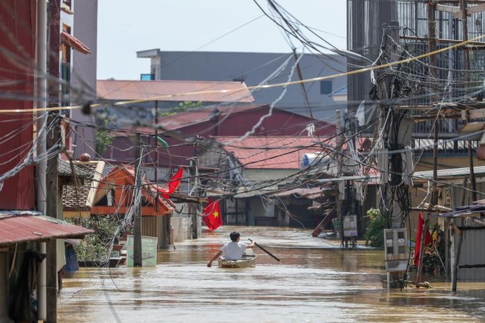 Hàng ngày các gia đình thay phiên nhau chèo thuyền lên mặt đê nhận nước, lương thực.