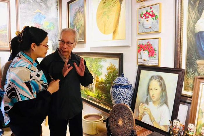 Họa sĩ ở làng Hải Minh (Ninh Bình) giới thiệu cho du khách các tác phẩm hội họa. (Ảnh: TRẦN LOAN)