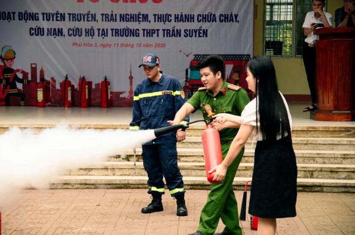 Nữ giáo viên Trường THPT Trần Suyền được hướng dẫn thực hành thao tác kỹ thuật chữa cháy bằng bình chữa cháy xách tay.
