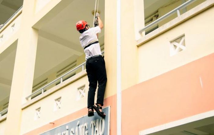 Học sinh thực hành thoát nạn từ trên cao xuống bằng dây hạ chậm.