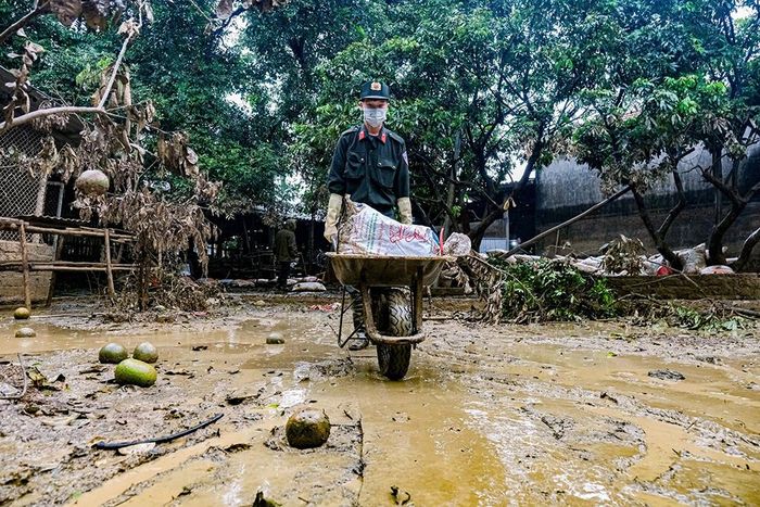 Cán bộ, chiến sĩ cảnh sát cơ động giúp gia đình bà Dung thu dọn xác gà trong vườn.