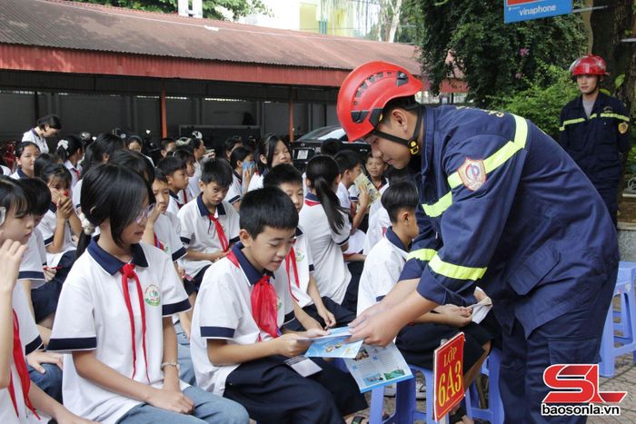 Cán bộ Phòng Cảnh sát PCCC và CNCH phát tờ rơi tuyên truyền kỹ năng PCCC cho học sinh.