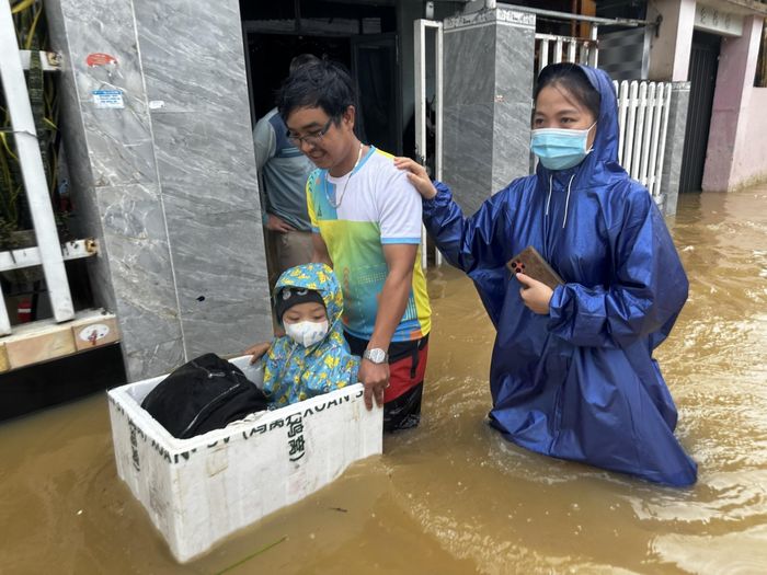 Vợ chồng anh Trần Văn Giang cho con vào thùng xốp để di chuyển ra khỏi khu vực ngập