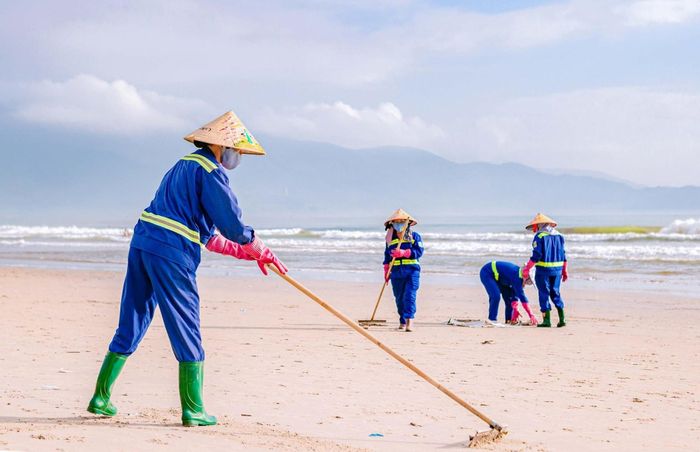 Công nhân môi trường khẩn trương dọn vệ sinh tại bãi biển Mân Thái sau bão số 13. Ảnh: BẢO LÂM