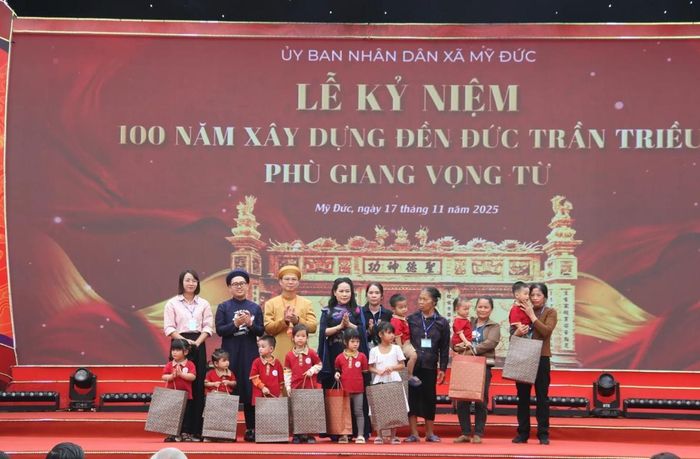 Bí thư Đảng ủy xã Mỹ Đức Đặng Văn Cảnh và bà Nguyễn Thị Thúy Hường tặng quà cho các cháu học sinh. Ảnh: hanoimoi