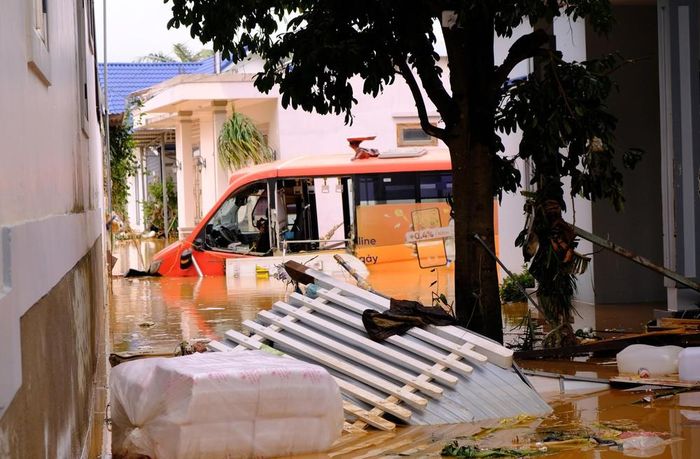 Một chiếc xe buýt của hãng vận tải bị nước lũ cuốn trôi dạt, va đập gây hư hỏng nặng. Ảnh: Nguyễn Dũng – TTXVN