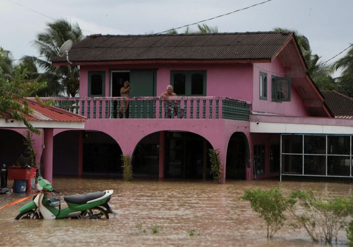 Tại Malaysia, mưa lớn tấn công 10 bang, buộc khoảng 18.000 người phải sơ tán tính đến ngày 25/11. Riêng bang Kelantan có hơn 9.700 người di tản đến 40 trung tâm cứu trợ, trong khi Selangor và Perak cũng chịu ảnh hưởng nặng nề. Người dân bị mắc kẹt trên tầng hai của ngôi nhà bị ngập lụt tại Kangar, Malaysia. Ảnh: Reuters.