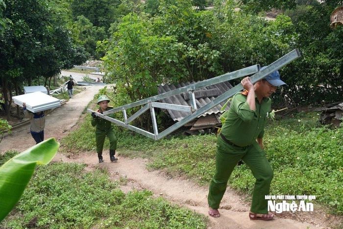 Các lực lượng Công an xã Mường Típ cõng vật tư làm nhà cho bà con sau lũ. Ảnh: Văn Trường