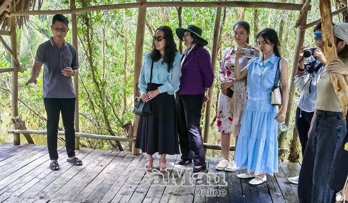 Hướng dẫn viên đang thuyết trình cho du khách về cảnh sinh hoạt được tái hiện trong Làng rừng.