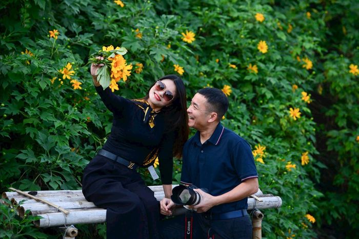 Du khách chụp hình bên vườn hoa dã quỳ sáng vàng rực rỡ - một khung cảnh lãng mạn, đầy chất thơ. Ảnh: Tuấn Anh