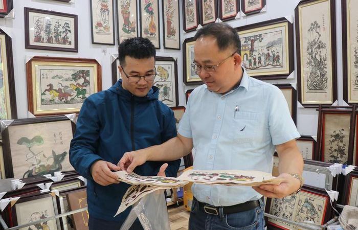 Khách tìm hiểu về tranh dân gian Đông Hồ tại phòng trưng bày của nghệ nhân ưu tú Nguyễn Thị Oanh ở phường Thuận Thành, tỉnh Bắc Ninh. Ảnh: Thái Hùng - TTXVN